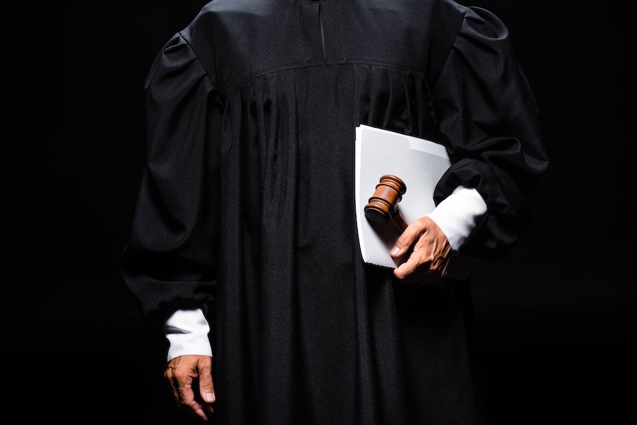 cropped view of judge in judicial robe holding gavel and papers isolated on black