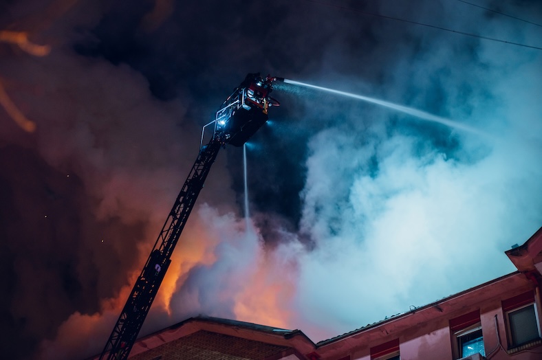Firefighter on pull-out crane put out a fire in a burning building