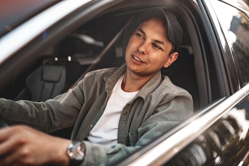 Young smiling man sitting in a car with open window